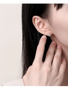Rose gold heart crown stud earrings featuring a sparkling center stone on a model ear
