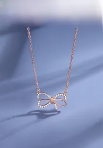 Détail du collier nœud en or rose avec zircons blancs sur fond violet ondulé