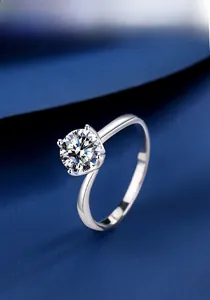 Detailed view of moissanite ring with a twisted silver band on blue silk fabric
