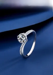 Detail of a 1 carat moissanite ring with a four-prong setting and side diamond accents