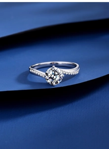 Macro shot of 1 carat moissanite bypass ring with pave setting on dark blue fabric
