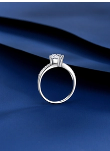 Detail view of four-prong moissanite ring with side accent diamonds on blue silk