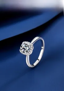 Macro detail of a 1ct moissanite silver ring featuring halo setting on blue silk fabric