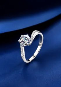 Detail of a 1-carat round cut moissanite ring with S-curve band on blue silk