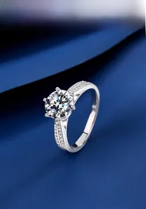 Vue détaillée d'une bague de fiançailles en moissanite à six griffes sur tissu bleu foncé