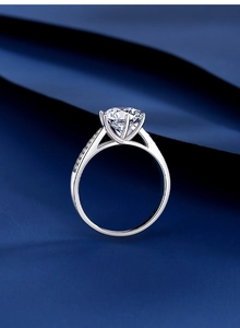 Gros plan d'une bague en moissanite à six griffes avec pierres latérales sur soie bleue