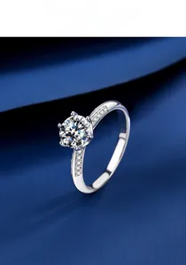 Detail of a six-prong moissanite engagement ring on luxury dark blue silk fabric