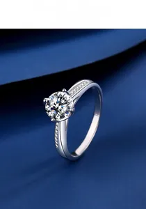 Détail d'une bague moissanite à six griffes avec diamants latéraux sur fond de velours