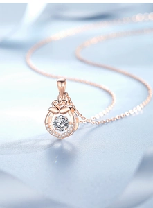 Macro detail of rose gold heart pendant necklace featuring a dancing center gemstone