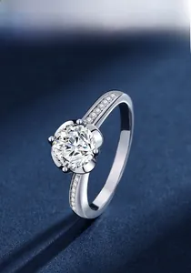 Detail view of round cut moissanite ring with six-prong setting and side accent stones