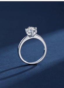 Detailed close-up of a classic six-prong silver moissanite ring with side accent diamonds