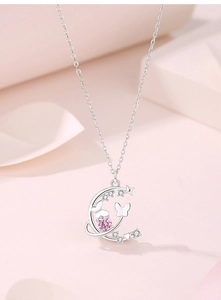 Gros plan d'un pendentif lune en argent S925 avec zircon rose et détails papillons