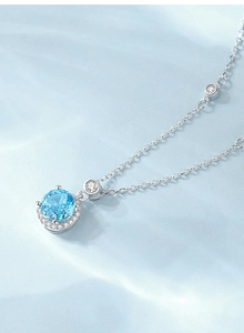 Gros plan du collier en argent S925 avec pierre ronde bleu clair et entourage de diamants