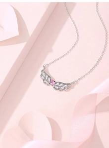 Detailed close-up of sterling silver angel wing pendant with pink heart gemstone