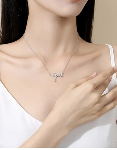 Close-up of S925 silver bow necklace with pavé stones and long tassel pendant on a model
