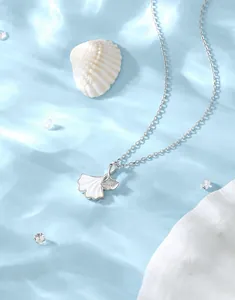 Vue macro d'un pendentif feuille de ginkgo en argent S925 avec nacre blanche sur l'eau