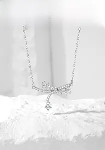 Macro shot of silver dragonfly necklace pendant with shimmering zircon tassels on white rock