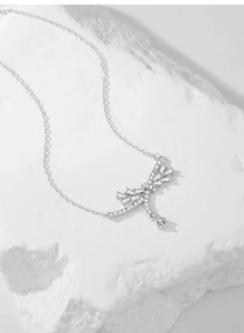 Macro view of S925 silver necklace with sparkling bow pendant on white stone