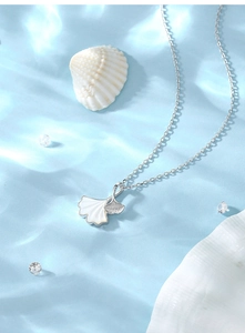 Détail du collier feuille de ginkgo en argent S925 avec nacre sur fond bleu ondué