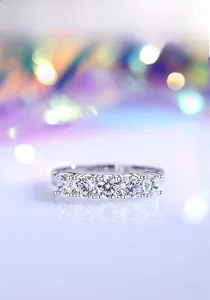 Macro shot of S925 silver ring featuring five brilliant moissanite stones with mirror reflection