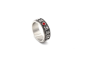 Macro detail of Buddhist mantra rotating ring with embossed scripts and red gemstone