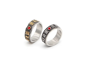 Detail of spinning stainless steel rings featuring etched mantra and ruby-like accents