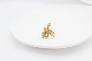Vue rapprochée d'une bague serpent dorée montrant les textures d'écailles sur plateau