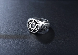 Detailed close-up of retro silver hexagram ring with embossed textures on dark background