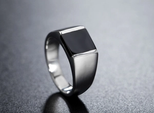 Macro shot of polished silver steel signet ring featuring a sleek rectangular black inlay