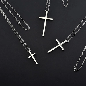 Detail of silver stainless steel cross pendant necklace on a black textured background