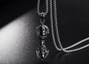 Macro detail of vintage silver Vajra pendant with antiqued finish on a dark necklace chain