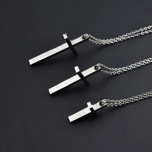 Three sizes of polished titanium steel cross pendants in silver finish on dark background