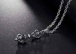 Macro detail of vintage silver vajra pendant necklace with fine religious carvings