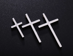 Detailed view of three polished stainless steel cross pendants in varying sizes