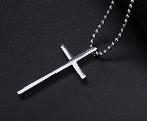 Macro shot of polished stainless steel cross pendant on silver ball chain with mirror finish
