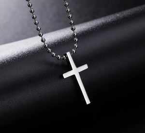 Close-up of minimalist polished silver titanium steel cross pendant on a ball chain