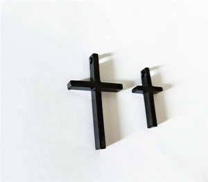 Detail view of two black titanium steel cross pendants in different sizes for necklaces