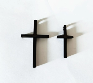 Detail view of two minimalist black titanium steel cross pendants in different sizes