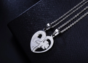Macro detail of stainless steel clover key and heart pendant with I LOVE YOU engraving