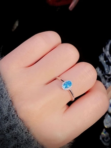 Detailed macro view of S925 silver ring featuring blue oval gemstone on model's finger