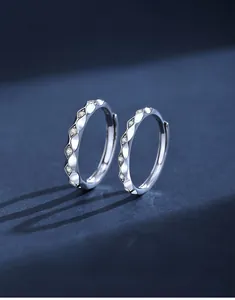 Macro detail of wave-shaped silver hoop earrings with sparkling cubic zirconia inlay