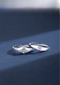 Macro detail of silver couple rings with princess cut white diamond and heart pink stone