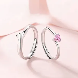 Détail de bagues de couple en argent S925 avec pierre cœur rose et design plume