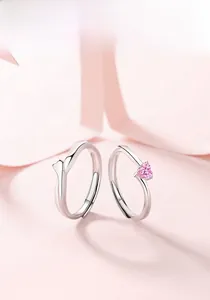 Dettaglio di anelli di coppia in argento S925 con pietra a cuore rosa su sfondo rosa
