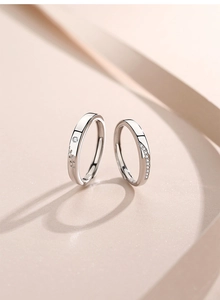 Detail of S925 sterling silver couple rings with leaf engraving and streamline diamonds
