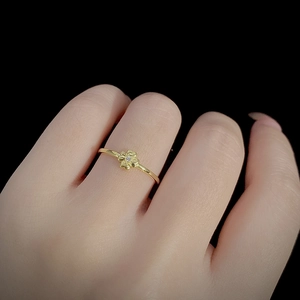 Elegant gold clover stacking ring with small central zircon on woman's finger