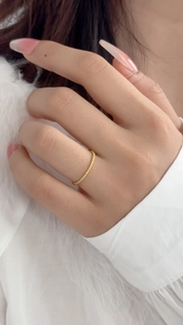 Close-up of minimalist gold twisted rope ring worn by a model with elegant long nails