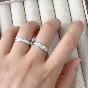 Matching feather engraved silver rings for couples worn on fingers high detail view