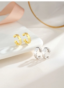 Détail des boucles d'oreilles en forme de C avec motif nid d'abeille or et argent