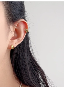 Close-up of a polished gold irregular C-shaped ear cuff and stud set for women